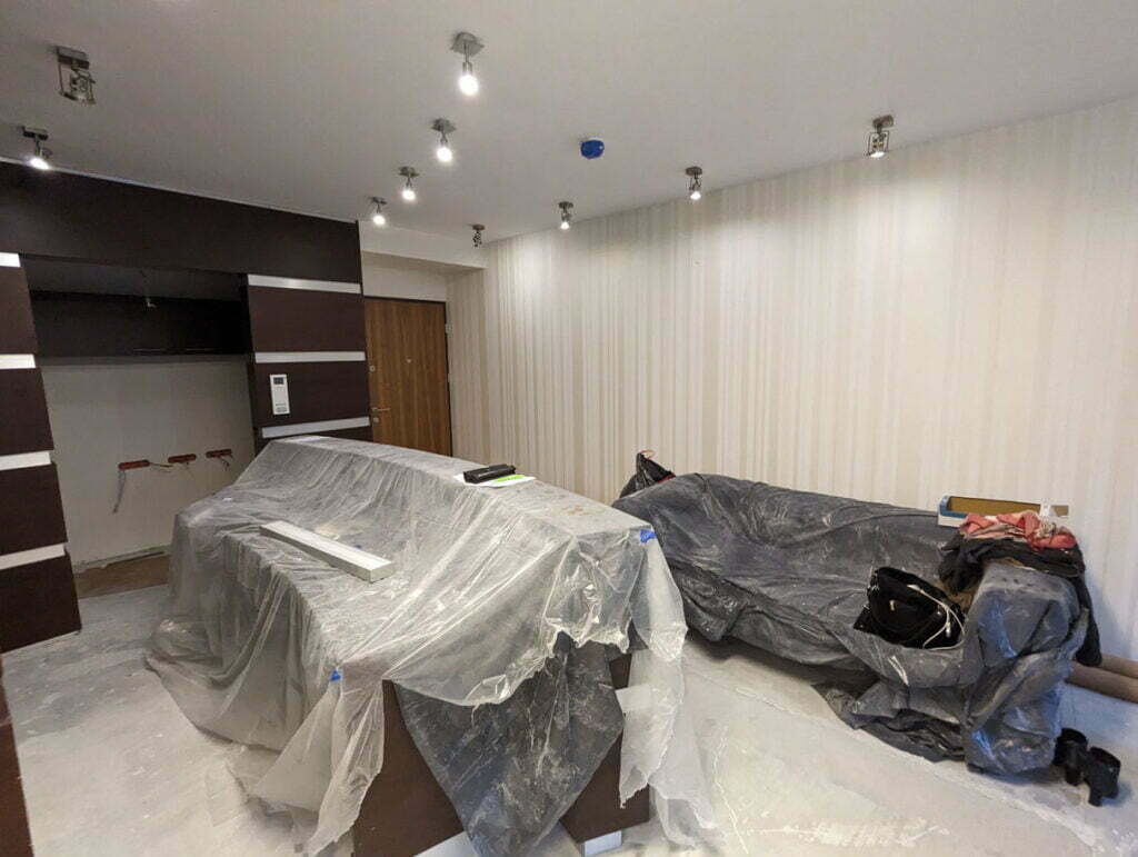 Wnętrze nowo wybudowanego domu Klienta Solid work czekające na sprzątanie. Meble przykryte folią