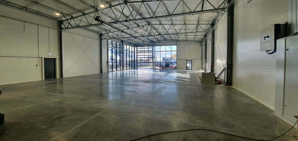 Czysta szara posadzka w obszernej hali salonu kamperów