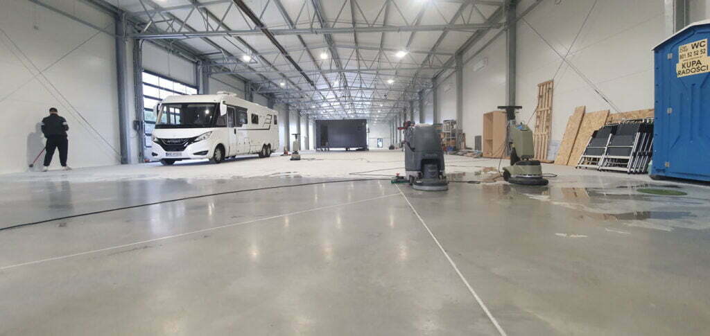 Czyszczenie posadzki w kolorze szarym w obszernej hali produkcyjnej