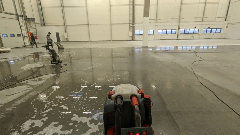 Maszynowe mycie i doczyszczanie szarej posadzki magazynowej