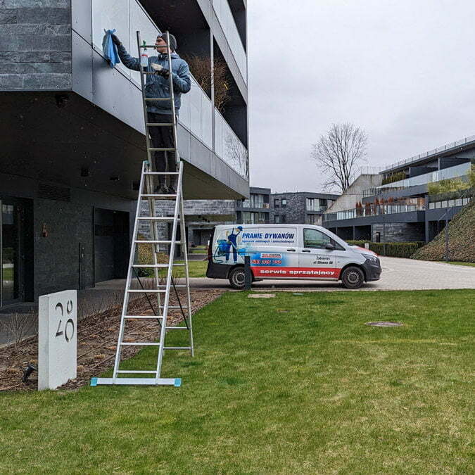 Pracownik firmy Solid Work w trakcie mycia balustrady apartamentowca.