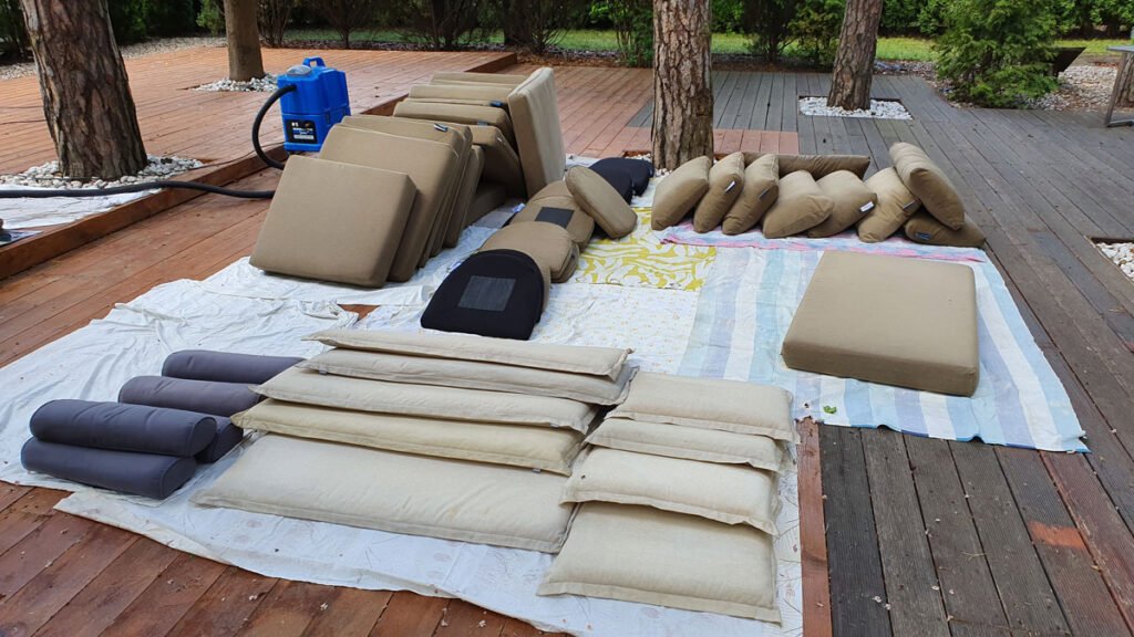 Starty poduszek ogrodowych w kolorze beżowym i granatowym - świeżo wyprane schną na tarasie wyłożone na czystych tkaninach