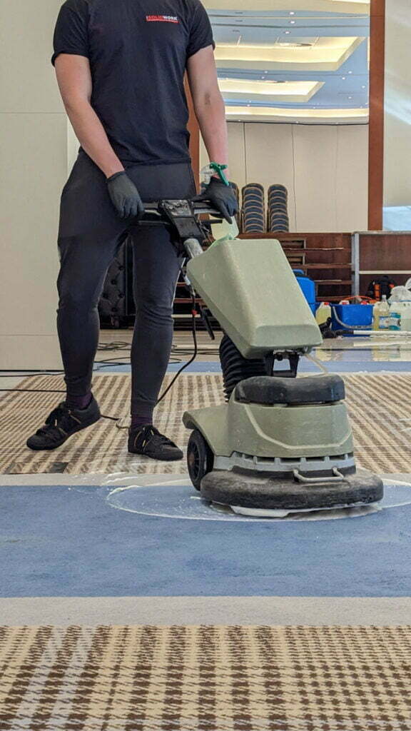 Pracownik Solid Work podczas prania wykładziny przy pomocy specjalistycznej maszyny